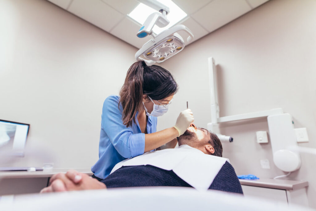 Female dentist examining a patient with tools.