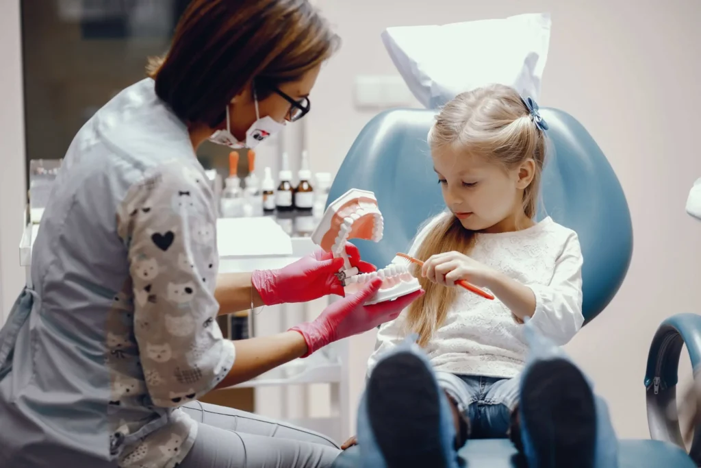 Little girl learning how to brush teeth on a model during a visit, showcasing family-friendly general dentistry at Dr. Kaltio Dental in Richmond, BC