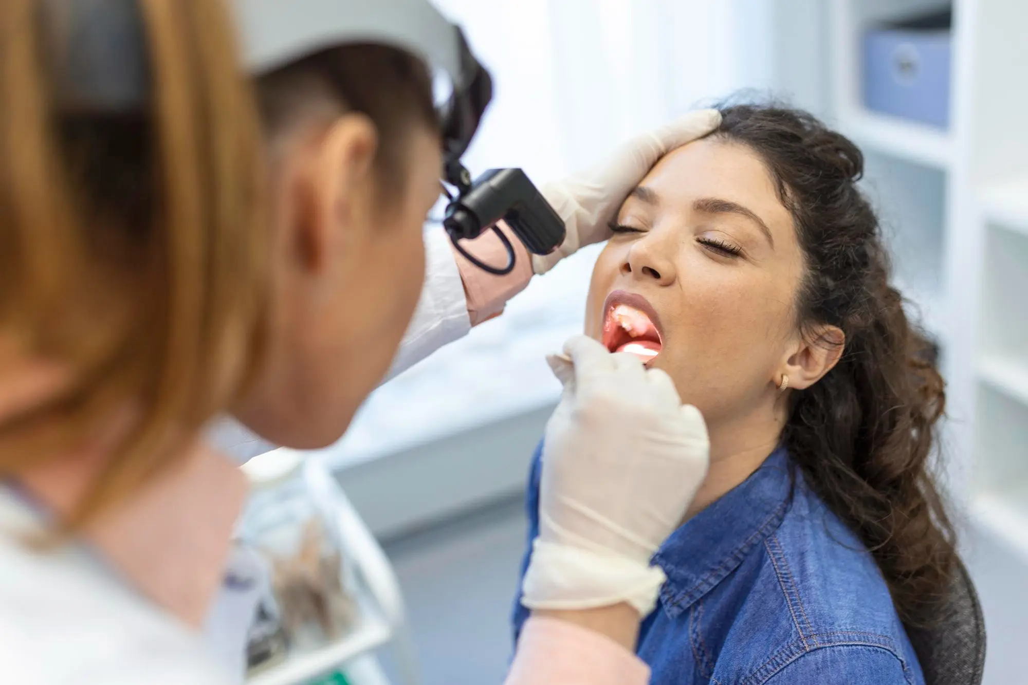 Dentist using a specialized headlamp light to perform a comprehensive gum disease examination on a patient at Dr. Kaltio Dental in Richmond, BC