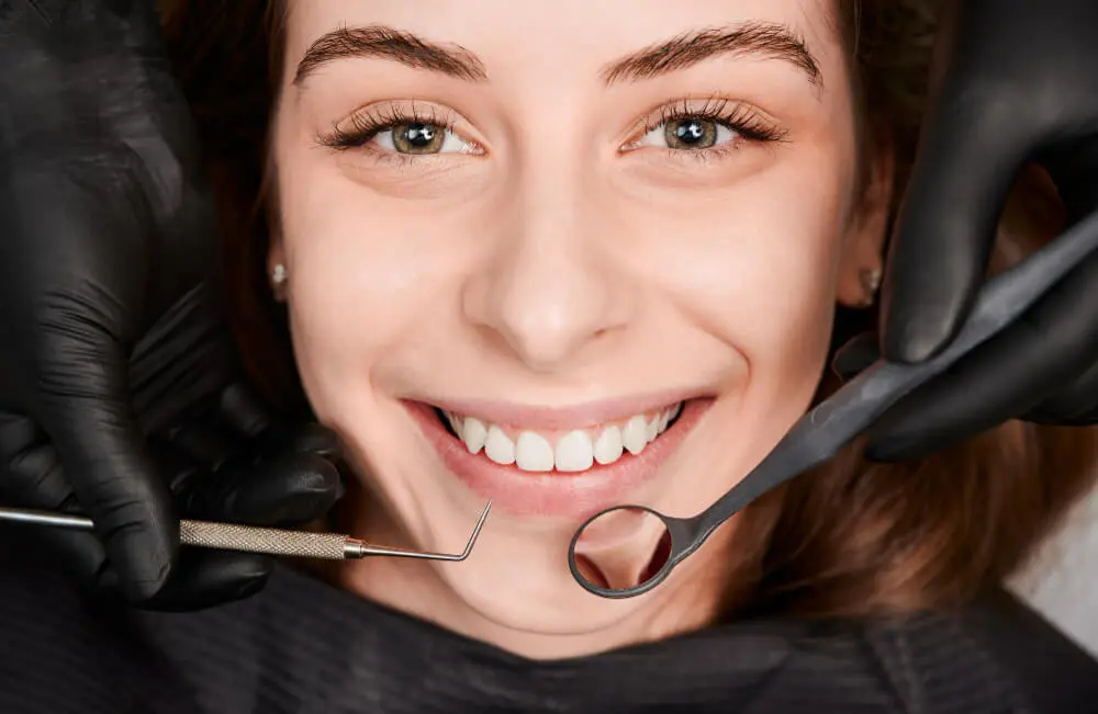 Close-up of a patient smiling during a professional dental cleaning and hygiene checkup with dental tools at Dr. Kaltio Dental in Richmond, BC
